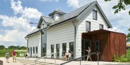 Photo of Chatham University students walking past the white dairy barn with solar panels on the roof at the Eden Hall campus.